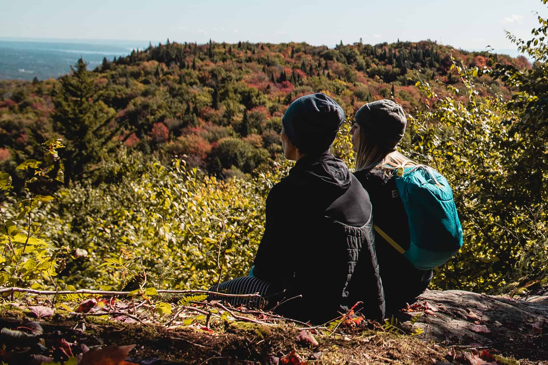 Deux femmes habillées en vêtement de randonnée sont assises et admirent la vue au sommet du Mont-Bélair.