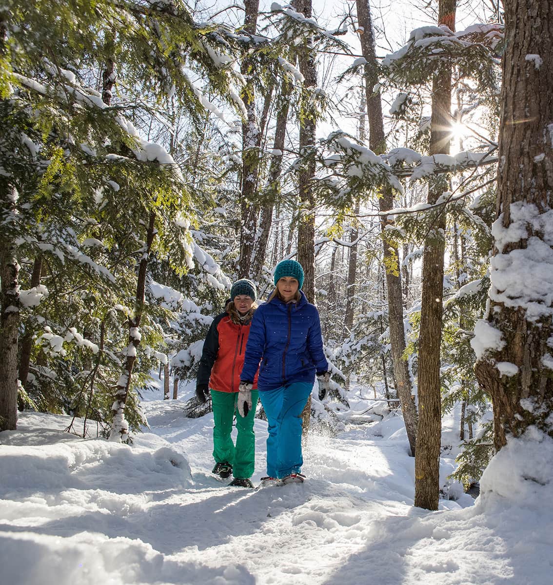 Deux femme en raquette dans un sentier l'hiver.
