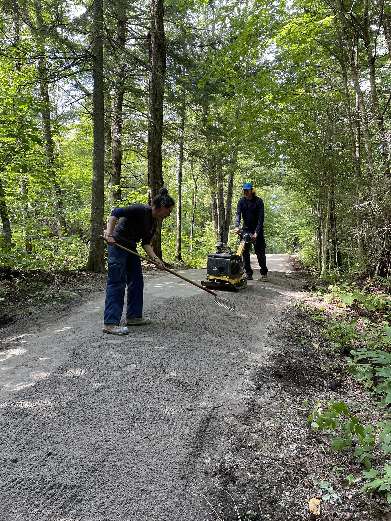 Deux employés qui râtellent le sentier de marche.